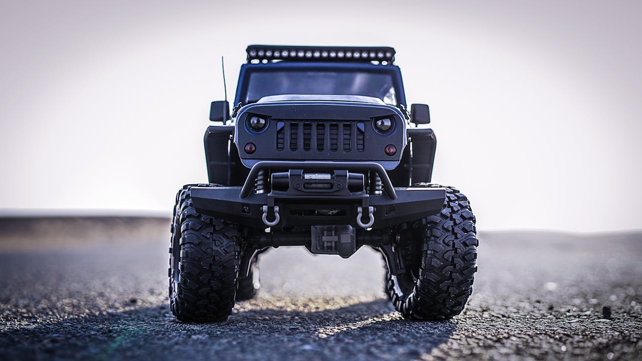 Detailed close-up of a miniature off-road toy car with rugged tires on a gravel surface.