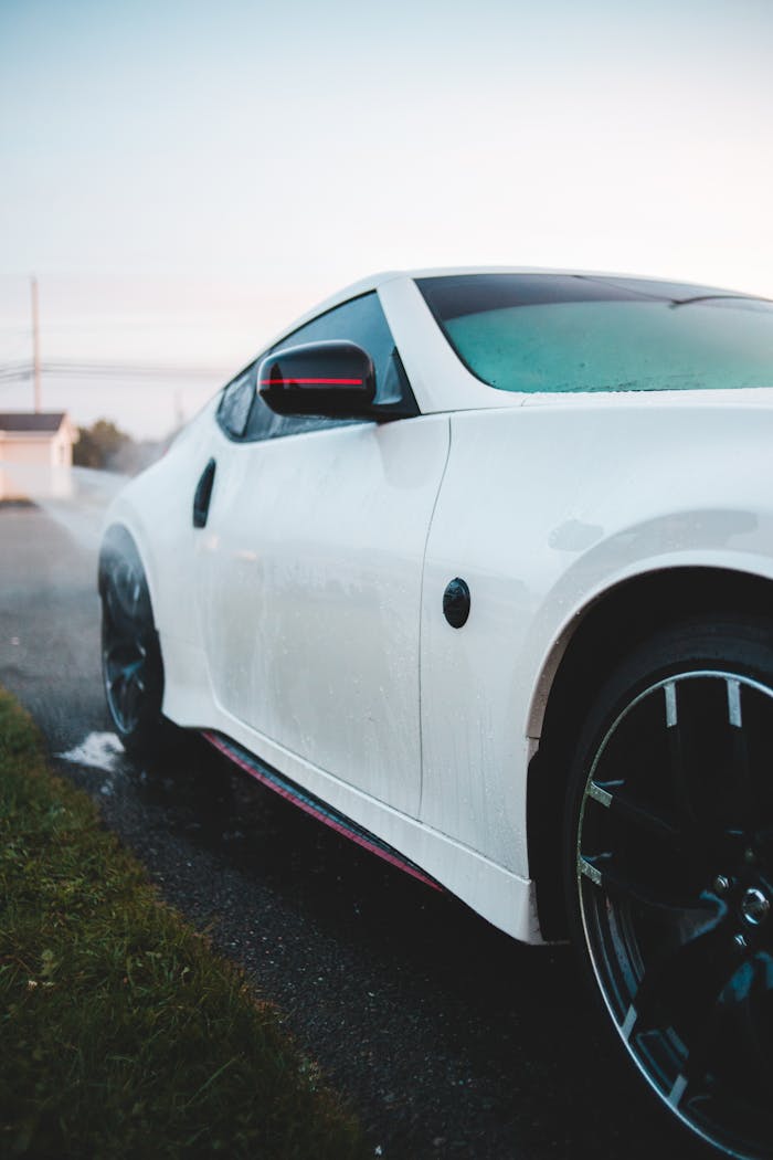 our-journey-02 Sleek white sports car with modern design parked on a wet pavement, showcasing luxury and style.